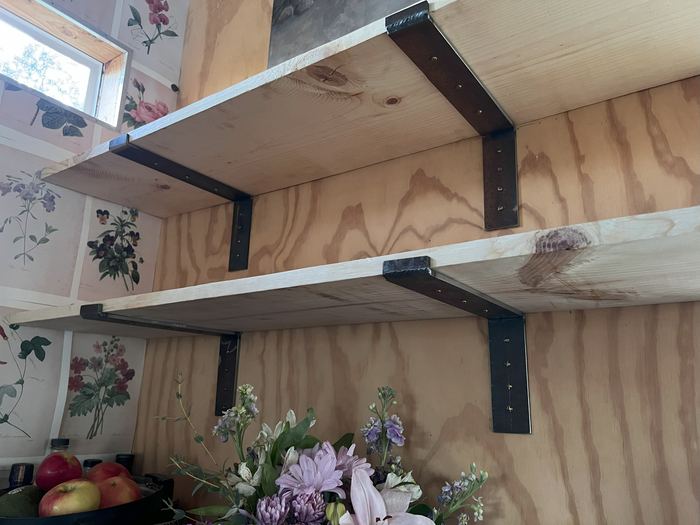 Steel shelf brackets under two wood shelves, seen up close