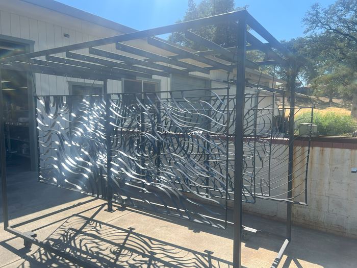 Topograin panels standing in a steel frame, casting contour-line shadows on the concrete