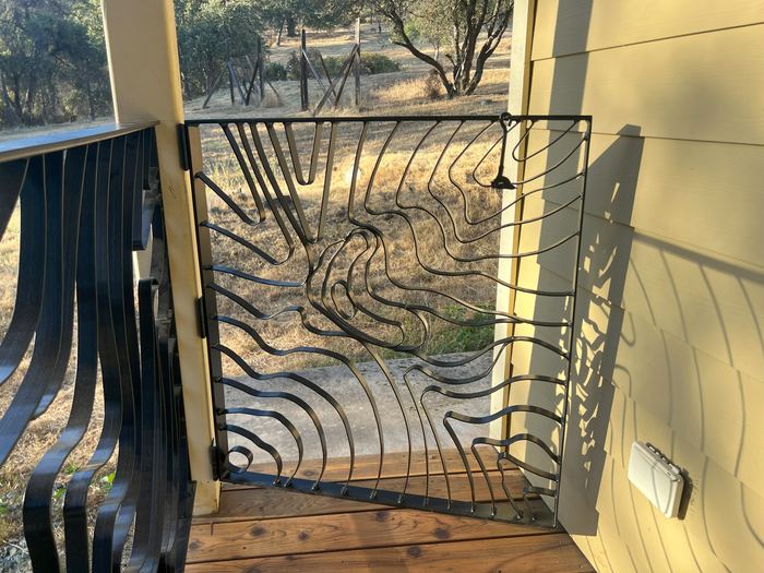 Small Topograin gate built into a porch railing at the top of the steps