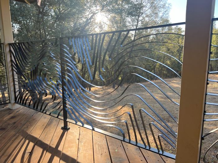 Late sun shining through a Topograin porch railing toward the trees