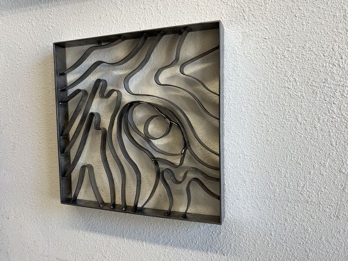 Topograin wall art at a slight angle, contour lines welded inside a steel frame